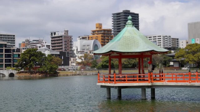Ohori Park panorama in Fukuoka, Japan, Chuo-ku ward, Kyushu island, with pond, Ukimi-do pavilion, bridges and city skyline near Maizuru Park, lake and promenade in a spring sunny day
