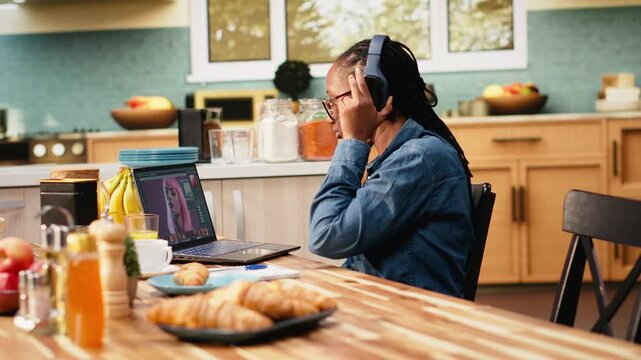 Woman editor works on a photograph on a laptop for post production, using image processing and color grading software. Creative process highlights graphic design skills during remote work at home.