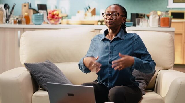 Young adult meditates and does breathing exercises for stress relief while working remotely on laptop at home. Digital nomad stays relaxed and calm during meditation break with eyes closed.