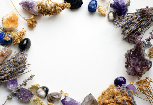 Natural amethyst, citrine, and schorl (black tourmaline) crystals, as well as dried herbs. Stone frame. Healing crystals. Copy space.