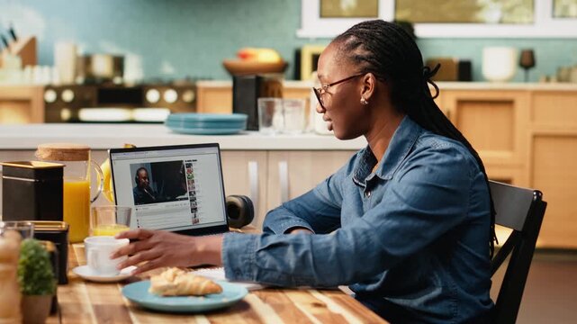 African american woman watches recorded online video content on laptop using a streaming platform for digital clips. Relaxed entertainment supports everyday life and lifestyle indoors at home.
