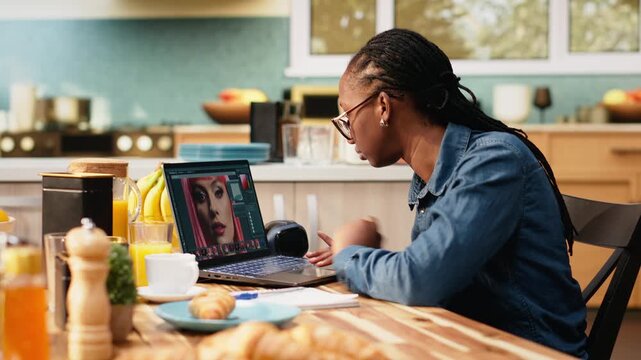 Woman photographer works remotely editing photos on a laptop for content creation. Photo editing software supports image selection and color grading adjustments in creative post production at home.