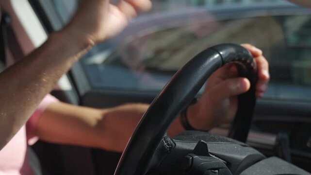 Man impatiently drums fingers and taps steering wheel with his hand inside car. Driving frustration, waiting in traffic and nervous driver behavior