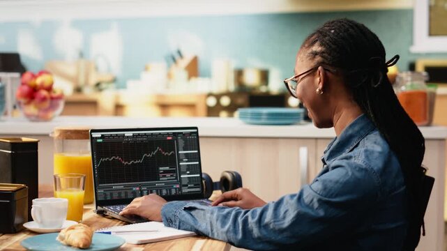Stockbroker woman at home monitoring market trends and day trading fluctuations, candlestick charts on laptop used to research risk for investments.