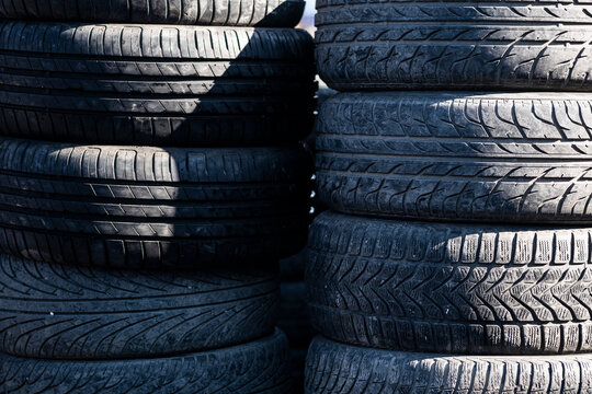 Stacks of old used car tires with worn tread patterns close-up