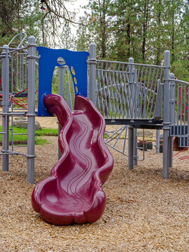 A purple plastic wavy slide at a playground