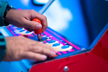 Player gripping a red arcade joystick and pressing buttons, close-up © janvaneyck