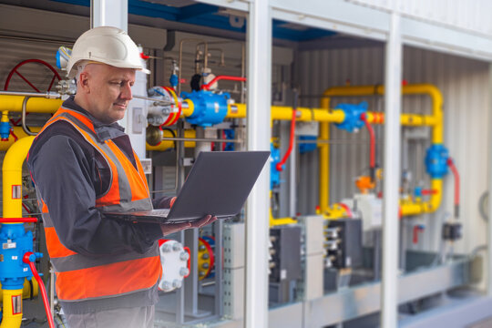 Gas industry, engineer monitors industrial gas distribution equipment with a laptop, checking pipelines, valves, pressure control and facility operation.