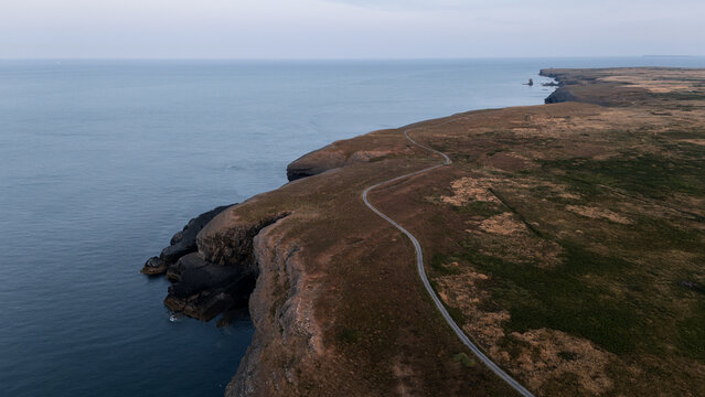 Aerial view over rocky seashore, Wales, showing rugged sea cliffs, rocky headlands and clear blue coastal water.