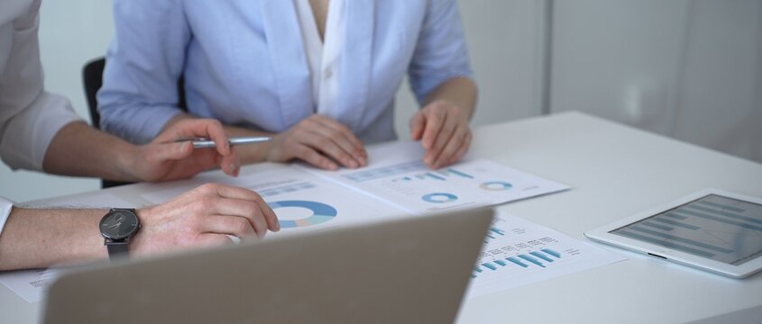 Business colleagues reviewing financial charts and marketing data during an important strategy meeting, analyzing sales reports and performance analytics for growth