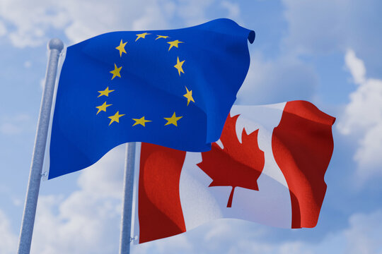 European Union and Canadian flags fluttering in the wind on flagpoles against a blue sky, representing international diplomacy, bilateral trade agreement, global partnership, and economic unity.