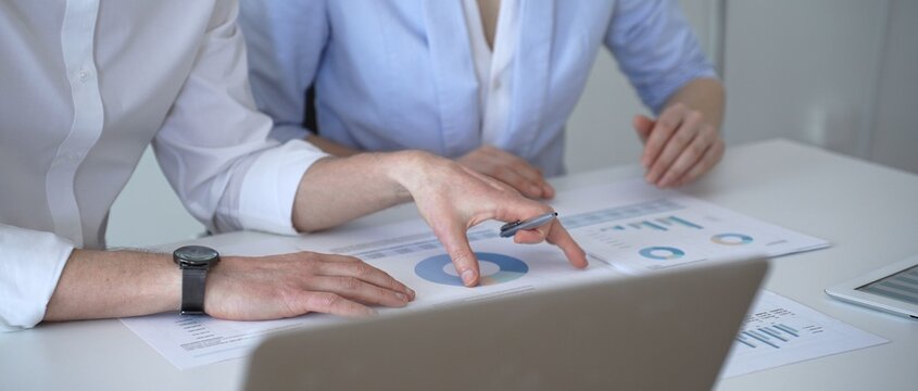 Business professionals analyzing financial data, discussing market trends and strategic reports during a corporate meeting in a modern office