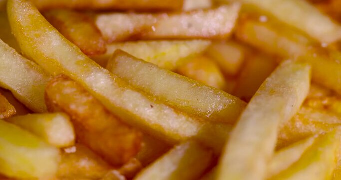 Crispy yellow french fries close up, pile of cooked potato french fries straws with oily texture after deep frying in hot fat