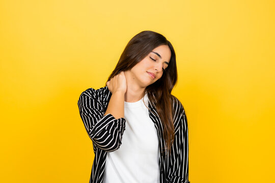 Woman standing with eyes closed, gently massaging her neck and shoulder to alleviate pain, stiffness, and discomfort, illustrating concepts of stress, injury, and poor posture