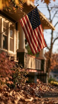 a serene autumn scene. The main subject is an American flag, prominently displayed in the foreground, with its iconic red and white stripes and blue stars. The flag is held aloft by a thin pole.