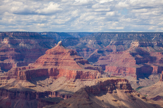 Grand Canyon layered red rock cliffs and deep canyon valleys beneath a textured cloud-filled sky, expansive geological landscape in Arizona, United States
