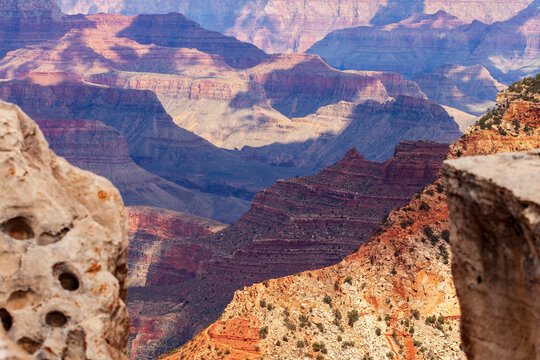 Layered Grand Canyon cliffs with colorful stratified rock formations and rugged stone foreground framing expansive desert canyon landscape in Arizona national park