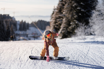 Fototapeta premium Snowboarder practices skills on a winter slope during a clear day in the mountains near a ski resort in the afternoon