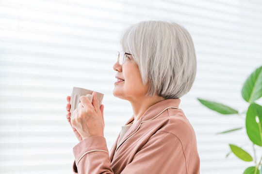 朝の光を感じながら温かい飲み物でくつろぐシニア女性。穏やかな老後と自分時間
