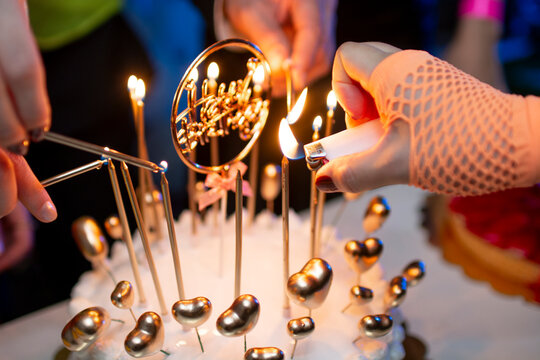 Manos encendiendo velas en pastel de feliz cumplea&ntilde;os en torta 