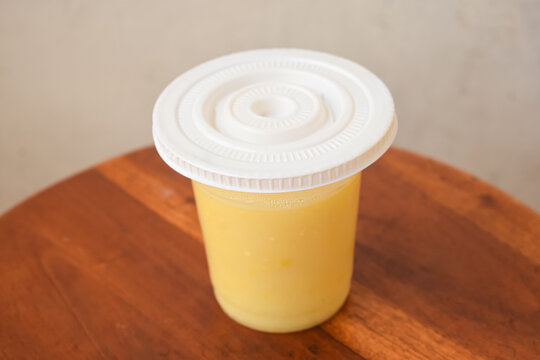 Fresh Mango Juice In Plastic Cup On Wooden Table
