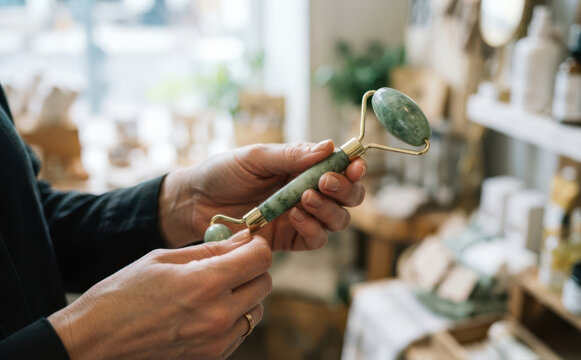 Woman holding a green jade facial roller for skin care massage and beauty treatment routine