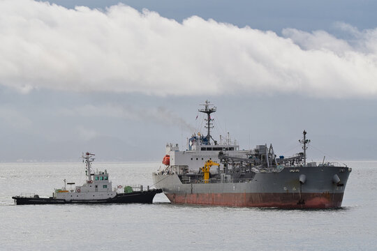 Cement carrier receiving tugboat assistance during port entry and berthing operations