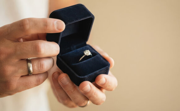 Man holding a velvet box with a diamond engagement ring proposing to marriage
