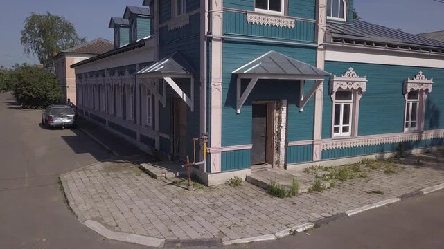 Low drone circles a blue wooden mansion