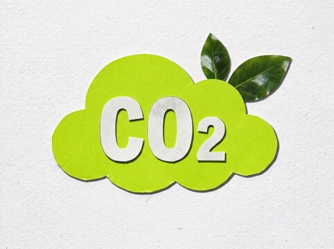 CO2 Carbon Emission Symbol with Green Leaves on Recycled Paper Background