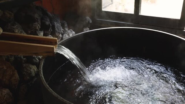 Traditional Japanese onsen interior, hot spring bathing experience in Beppu, Oita, Kyushu island, Japan, with steaming mineral water, stone tubs and wooden fixtures, authentic ryokan wellness ritual