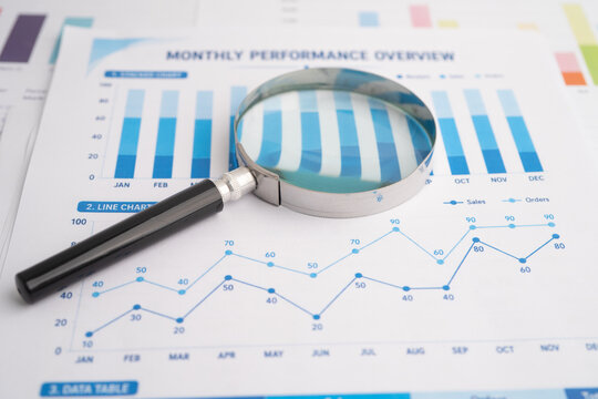 Magnifying glass on spreadsheet and graph paper.