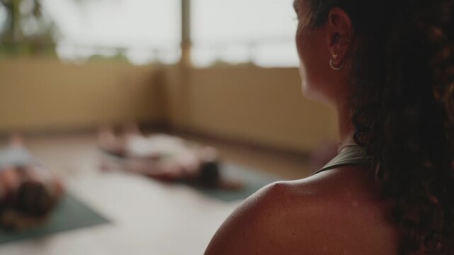 Yoga instructor watching over students relaxing in savasana pose during a wellness retreat