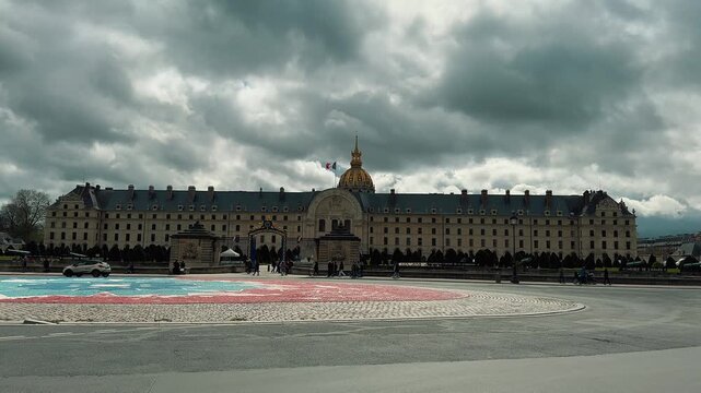 Tourists visit the grand courtyard of Les Invalides in Paris, showcasing magnificent French classical architecture, ornate stone arcades, an antique clock, the famous bronze Napoleon Bonaparte statue
