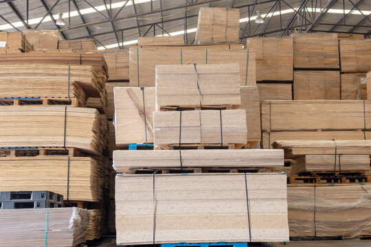 Abstract wood background. Full frame background of neatly stacked square wooden beams in a lumberyard, wood factory. Close up of texture and ends of sawn timber blocks arranged in bundles. Rows of squ