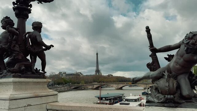 Sculptures on Pont Alexandre III overlook the Seine River and distant Eiffel Tower with cruise boats sailing under cloudy Parisian skies during a scenic daytime visit to France.


