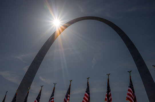 ST. LOUIS, MISSOURI &mdash; JULY 3, 2018: The sun shines beside the Gateway Arch above a row of American flags at Gateway Arch National Park.