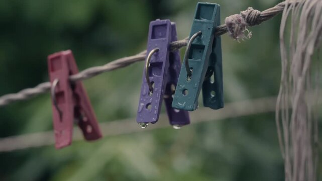 Plastic clothespins with water drops hanging on clothesline outside after rain