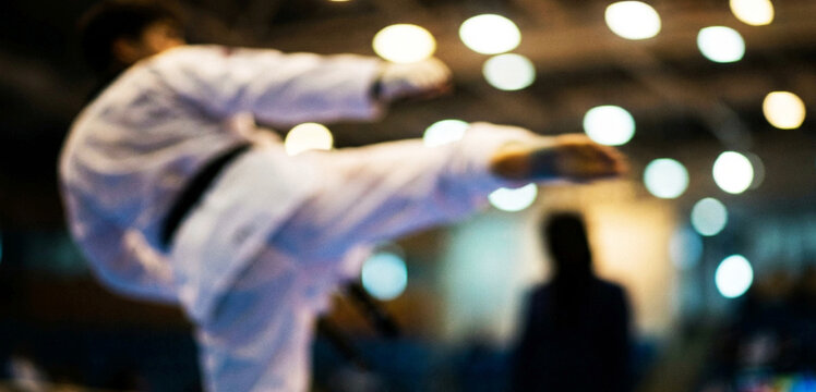 A dynamic karate practitioner executing a high kick in a competitive setting, capturing the energy and intensity of martial arts in action.