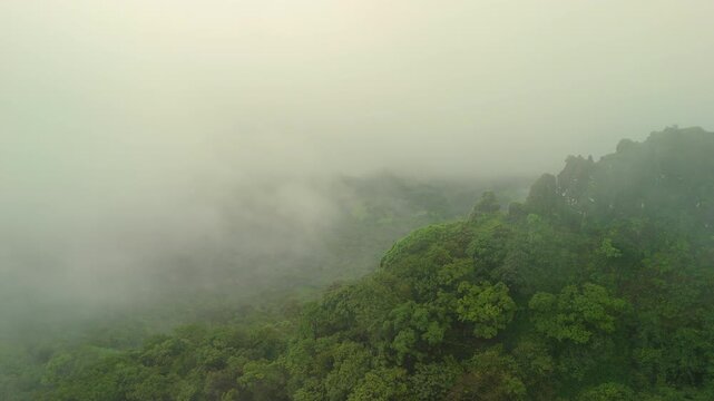 Drone pushes toward razor-sharp basalt ridge wrapped in morning monsoon mist; cinematic Sahyadri