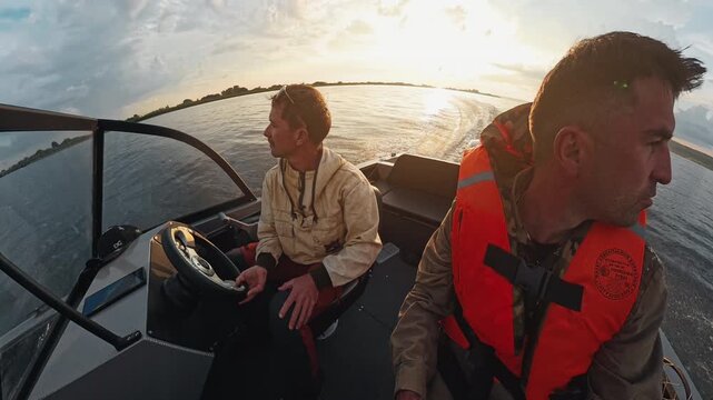 Two fishermen explore the river on the speed motor boat