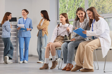 Fototapeta premium Healthcare consultation and patient care, doctor discussing medical records with young women in a modern clinic waiting room for health checkup