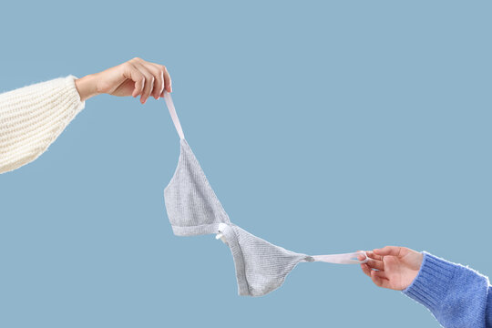 Body positivity and self love, two women holding a comfortable cotton bralette to promote inclusive fashion and healthy body image on blue background
