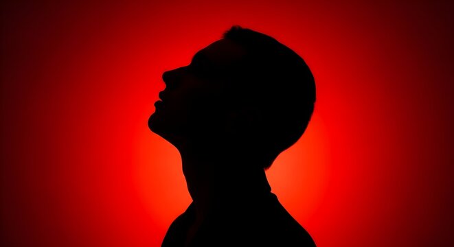 Dramatic Silhouette Profile of a Man Looking Up Against a Vibrant Red Circular Glow, ideal for psychological thrillers, dramatic posters, or conceptual marketing.