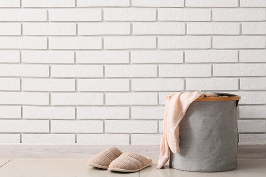 Household chores and laundry day, cozy slippers and clothes basket near a white brick wall for home organization and domestic routine lifestyle