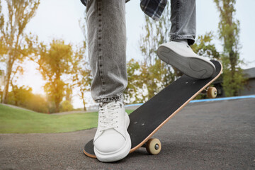 Legs of young man with skateboard in park, closeup © Pixel-Shot