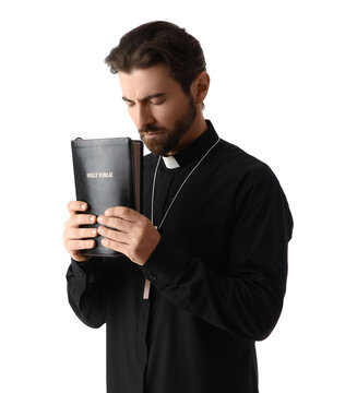 Handsome priest with Holy Bible praying on white background