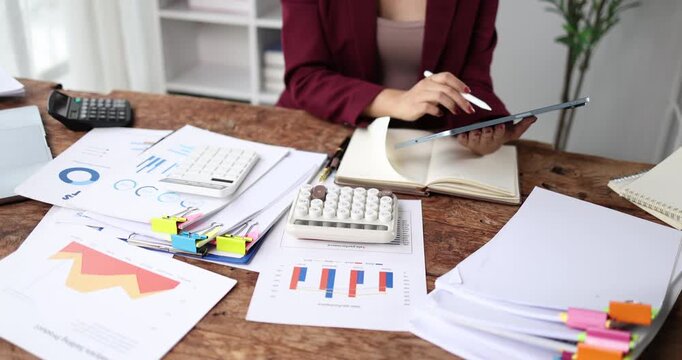Businesswoman analyzing financial reports and accounting data, using a calculator and digital tablet for strategic planning and economic success in the modern office