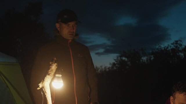 Group of men camping in the wild and gather near the bonfire and talk with each other. Fishermen camping and talk stories at night