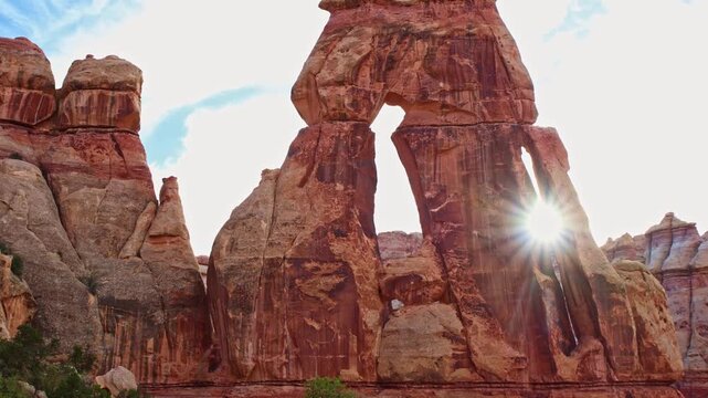 Bright morning sunburst flares through the dramatic openings of towering Druid Arch in the Needles District of Canyonlands Utah